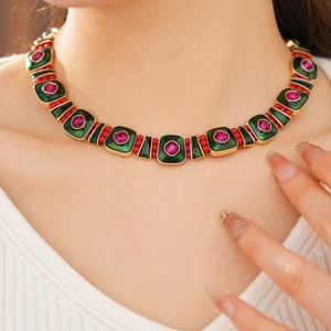 Close-up of a vintage gold necklace with green square pendants and red gemstone details