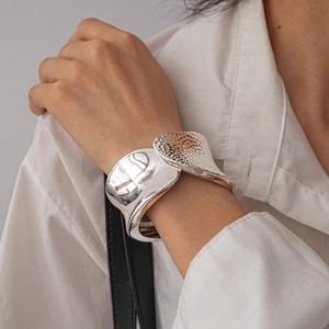 Close-up of a silver irregular crumpled cuff bracelet on a model wearing white