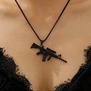 Detail of a matte black assault rifle pendant necklace worn by a model with a lace collar