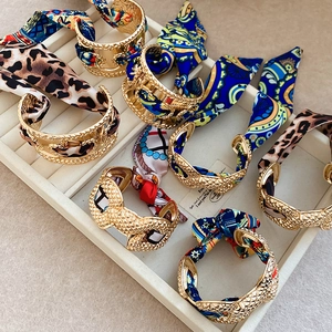 Detailed macro view of gold metal bangles wrapped with various silk scarves and patterns
