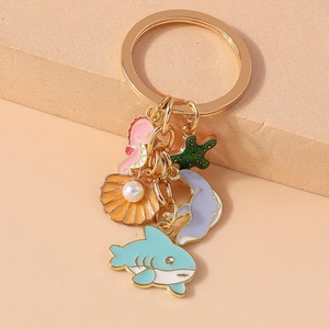Detail of gold keychain featuring enamel sea creatures like seahorse, starfish and whale