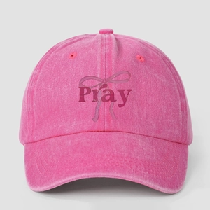 Pink washed denim baseball cap featuring Pray text and bow print in a vintage street style