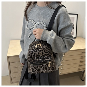Detailed view of mini leopard print backpack with plush texture and gold zippers