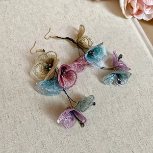 Detailed view of floral fabric tassel earrings with pastel petals and gold hooks
