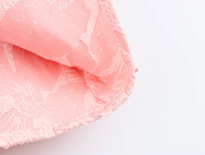 Dettaglio macro del tessuto jacquard floreale rosa con delicati bordi a volant e cuciture