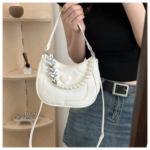 Detail of white half-moon underarm bag with pearl chain and embossed heart detail