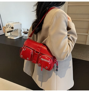 Detail of red vegan leather shoulder bag featuring silver utility buckles and pockets