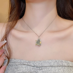 Detail of silver chain necklace featuring green stone pendant with yellow wire flowers
