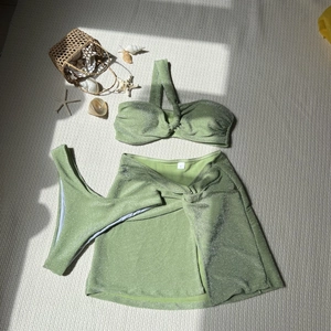 Detailed view of mint green three-piece shimmer bikini with knotted skirt and size S label