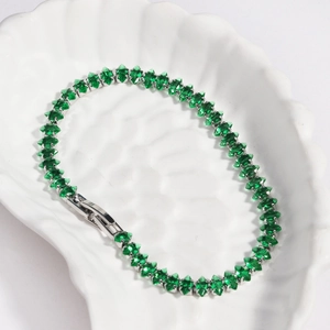 Macro detail of silver tennis bracelet featuring green marquise-cut zircon stones