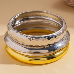 Close-up of three-piece set with gold and silver geometric wide band metal bracelets