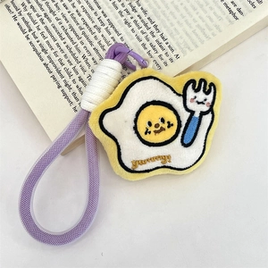 Macro detail of plush fried egg keychain with yummy embroidery on an open book