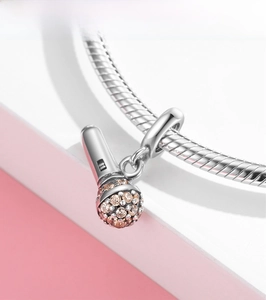 Detailed view of silver microphone pendant with champagne pavé crystals on a bracelet