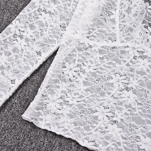 Close-up of white floral lace fabric with intricate crochet details on a gray background
