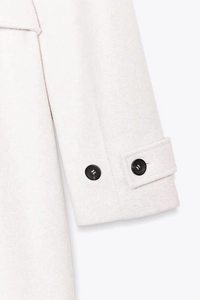 Detailed macro view of soft pink wool coat sleeve with decorative black contrast buttons