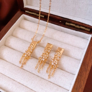Detailed macro view of 18K gold-plated leaf fringe necklace and earrings set
