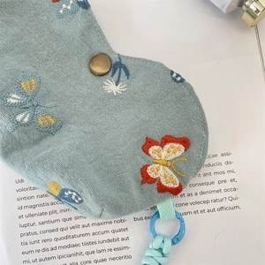 Détail de la broderie papillon sur pochette à lunettes en tissu bleu clair avec bouton