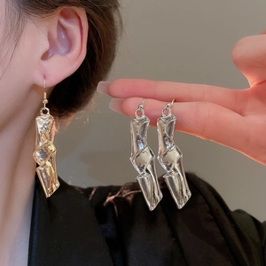 Detail of chunky twisted irregular geometric metal earrings in gold and silver finish