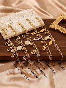 Dettaglio di bracciali placcati oro 18k con ciondoli floreali e geometrici su seta lussuosa