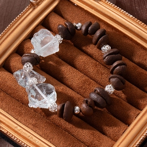 Detail of coffee bean beads and clear irregular crystal stones in a golden jewelry box