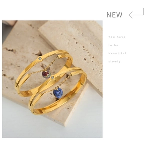 Detail of gold double-layer steel bracelet featuring a heart natural stone pendant
