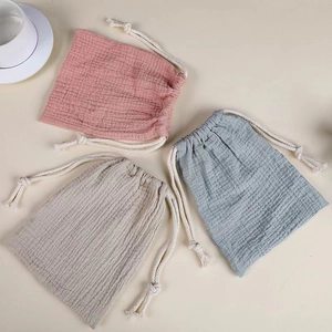 Detailed macro view of three cotton muslin drawstring pouches in pastel colors set