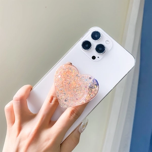Close-up of heart-shaped glitter phone socket holder with pink sequins on white phone case