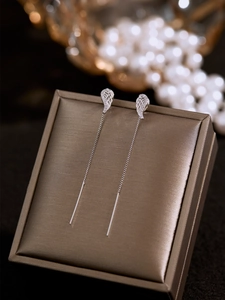 Detailed view of silver wing long tassel earrings on brown velvet jewelry case