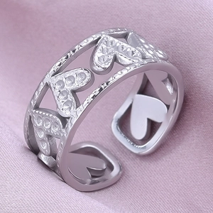Macro shot of silver hollow heart pattern ring with frosted texture on pink silk fabric