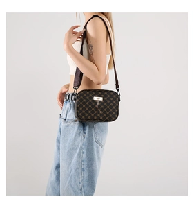 Deep brown crossbody bag with retro floral pattern and wide shoulder strap on model