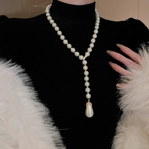 Detailed close-up of a luxury white pearl Y-necklace with a gold water drop pendant