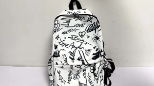 Detail of white backpack with black graffiti art lettering and minimalist street style