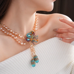 Detail of vintage peacock necklace with colored rhinestones and champagne beaded chain
