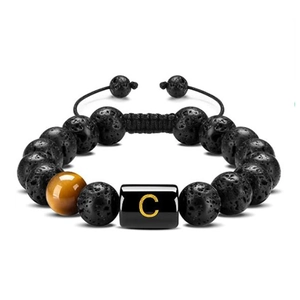 Detailed texture of 10mm lava stone and tiger eye bead with gold letter C engraving