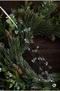 Detail of faceted acrylic icicle ornaments hanging on a pine needle and pinecone wreath