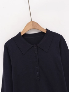 Dettaglio del colletto polo blu navy con bottoni coordinati su maglia a trama fine