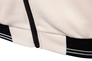 Detailed macro view of the black zipper and striped ribbed hem on a beige jacket