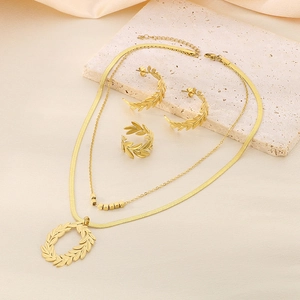 Détail de parure bijoux feuille d'olivier dorée avec collier double, boucles et bague