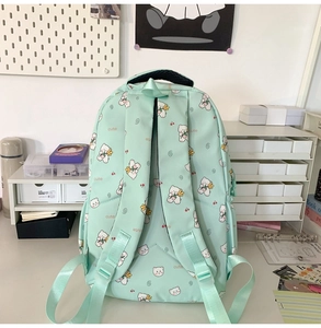 Detail of mint green schoolbag with cute bear print on a student desk setting