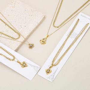 Close-up of golden double-layer necklace with crown and heart-shaped diamond pendants