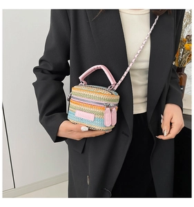 Dettaglio borsa a secchiello in paglia intrecciata multicolore con manici in pelle rosa