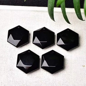 Five hexagonal faceted black obsidian crystal pendants on white textured background