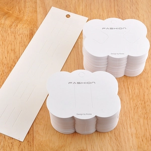 Close-up of cloud-shaped and rectangular white paper jewelry display cards on wood