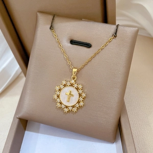 Macro detail of gold cross pendant with white mother-of-pearl inlay and sparkling diamonds