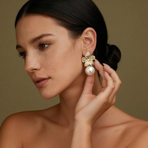 Elegant gold flower earrings with large pearls and crystal center worn by a model