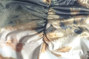 Detailed macro view of tie-dye fabric texture and pleated craftsmanship on the skirt
