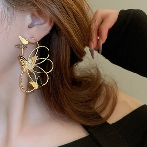 Close-up of a model wearing large hollow butterfly earrings in vintage gold metal