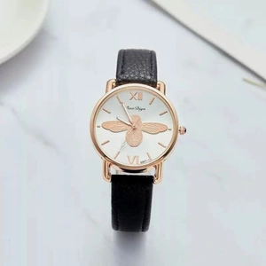 Detail view of white watch face with gold bee motif and rose gold stainless steel case