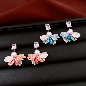 Détail macro de boucles d'oreilles vintage en émail et perles en forme d'éventail