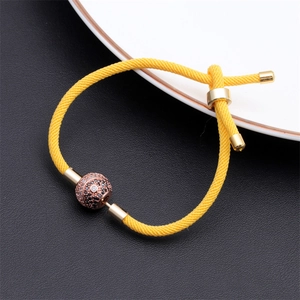 Detail of yellow braided rope bracelet with a rose gold pavé ball set with cubic zirconia